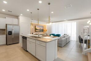 A modern kitchen with a central island, built-in appliances, and pendant lighting. - Disney 5BR Resort Home + Lazy River & Mini Golf (Davenport)