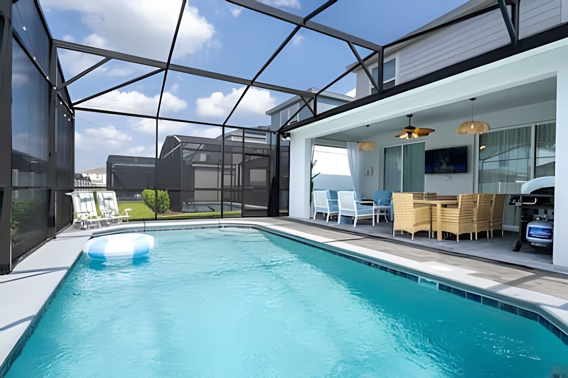 A modern indoor pool area with clear glass walls, a pool, and a seating area with a table and chairs.