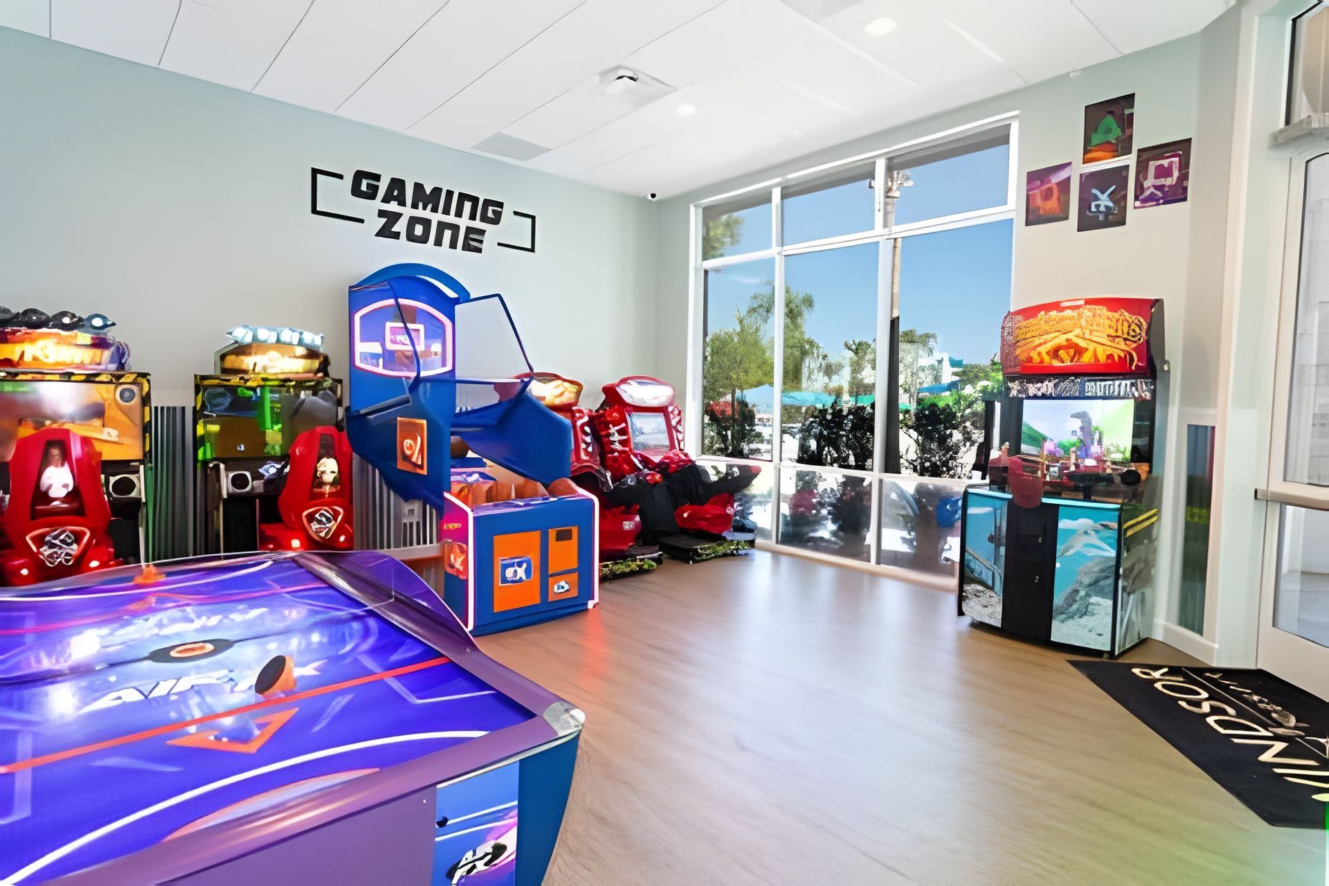 A gaming zone with arcade machines, a pool table, and large windows offering a view of the outdoors.