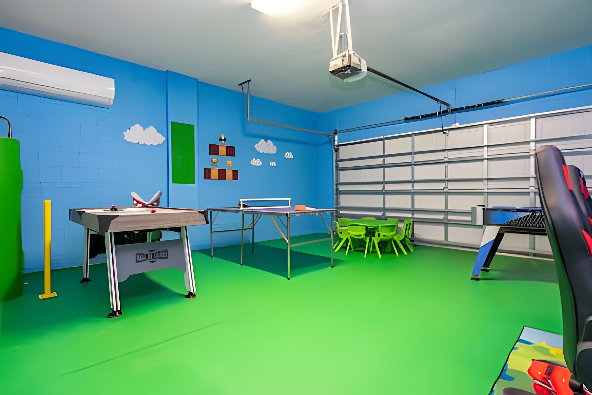 A room with a ping pong table, green chairs, a projector, and a garage door.