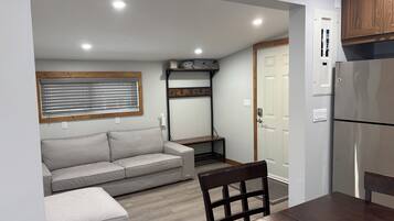 Una kitchenette compacta con refrigerador, horno integrado y repisa de madera sobre el horno.