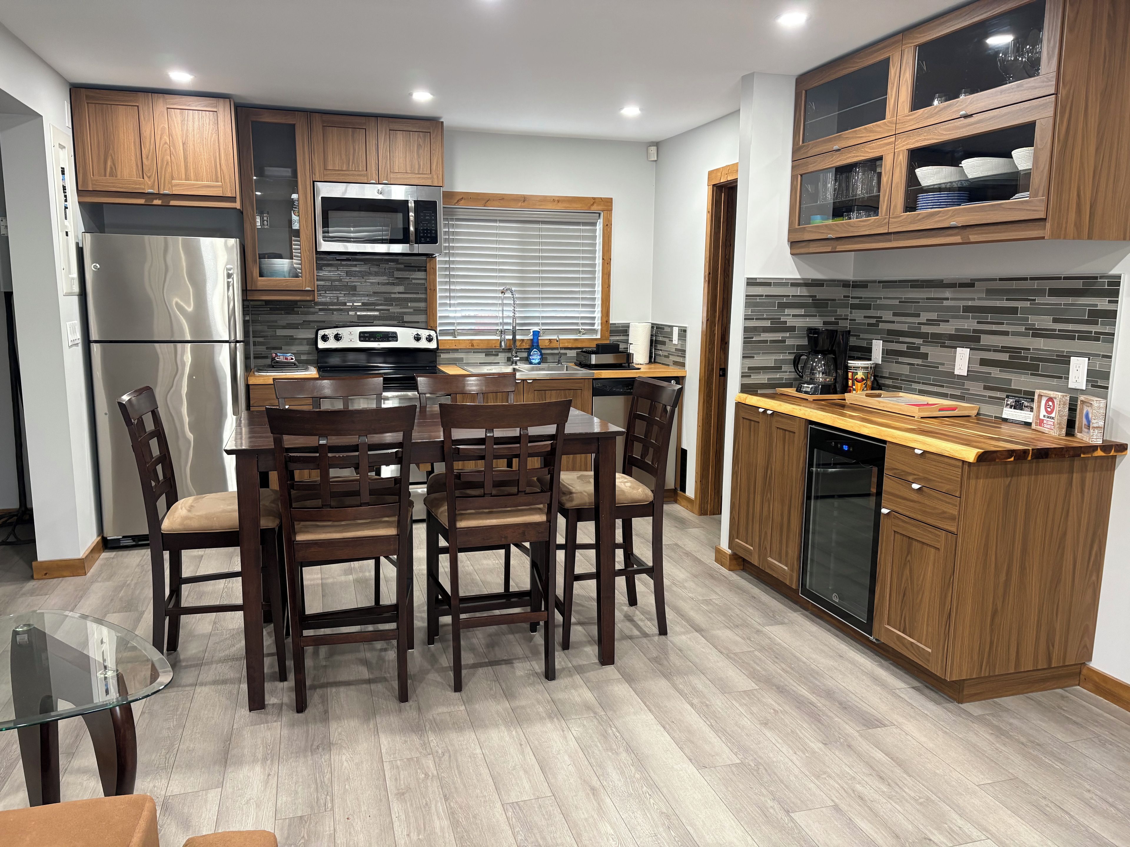 Una cocina moderna con armarios de madera, refrigerador de acero inoxidable, microondas integrado y lavavajillas.