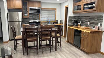 Una cocina moderna con armarios de madera, refrigerador de acero inoxidable, microondas integrado y lavavajillas.