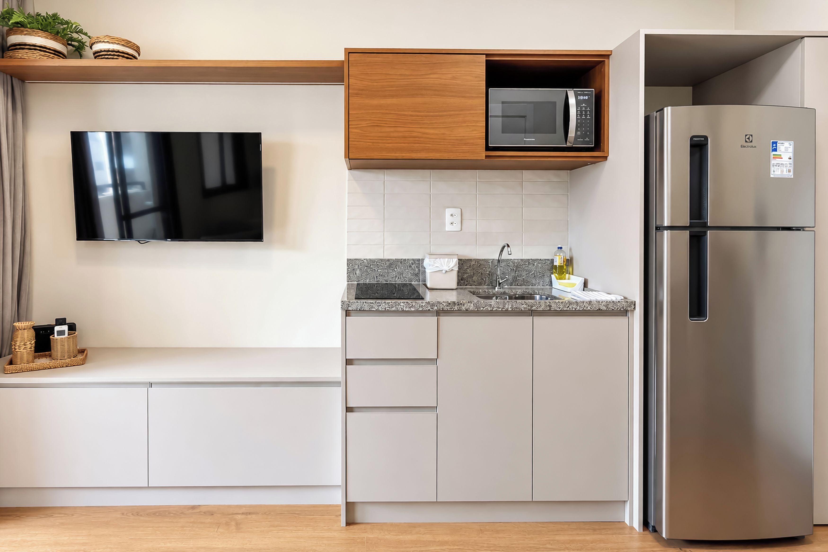 Una cocina moderna con televisor de pantalla plana, microondas y refrigerador de acero inoxidable.