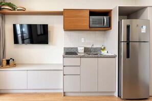 A modern kitchen with a flat-screen TV, a microwave, and a stainless steel refrigerator. - StayHome Aimberê - Gym & Pool (São Paulo)
