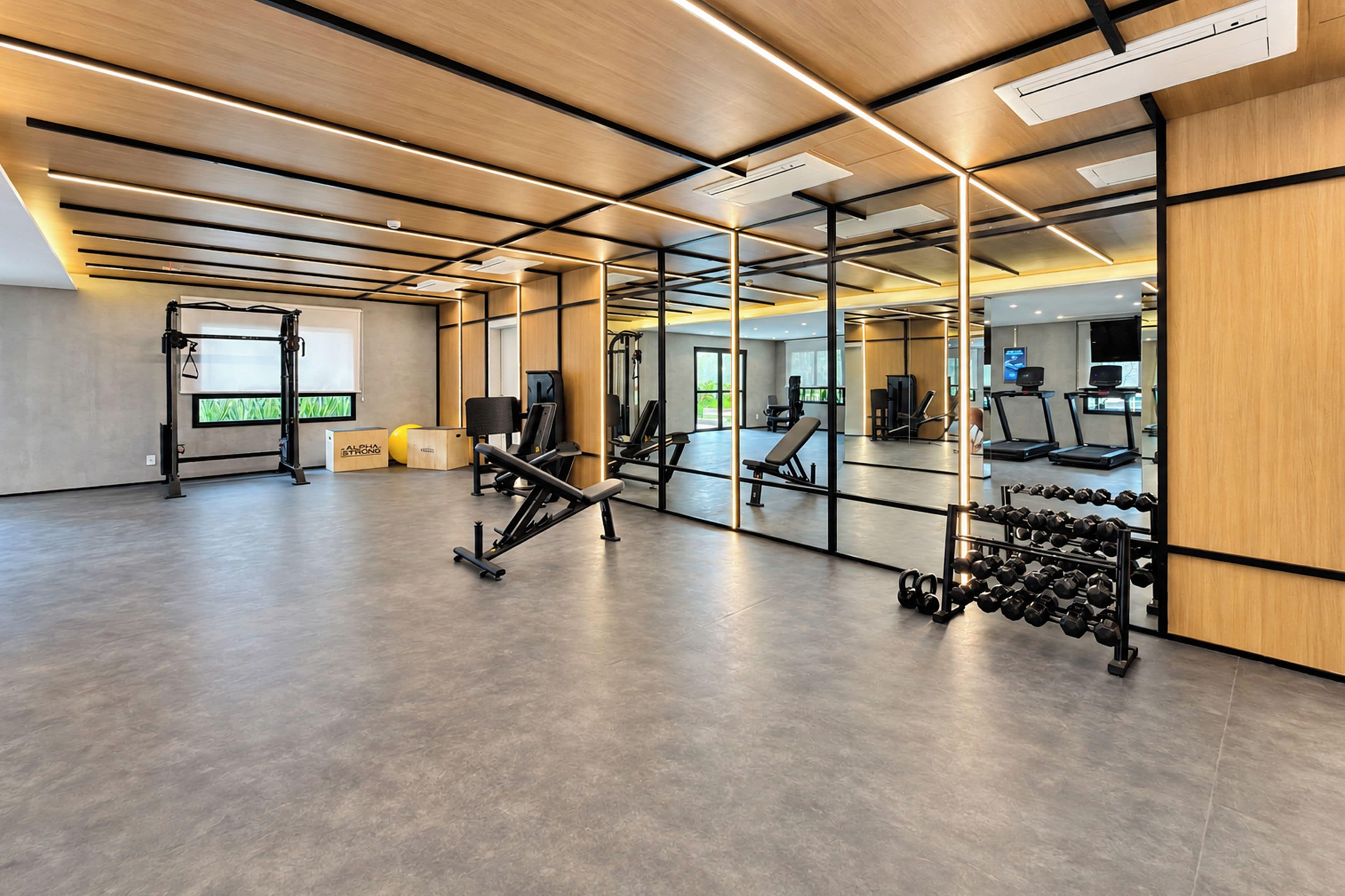 A modern gym with exercise equipment, a mirror wall, and a wooden floor.