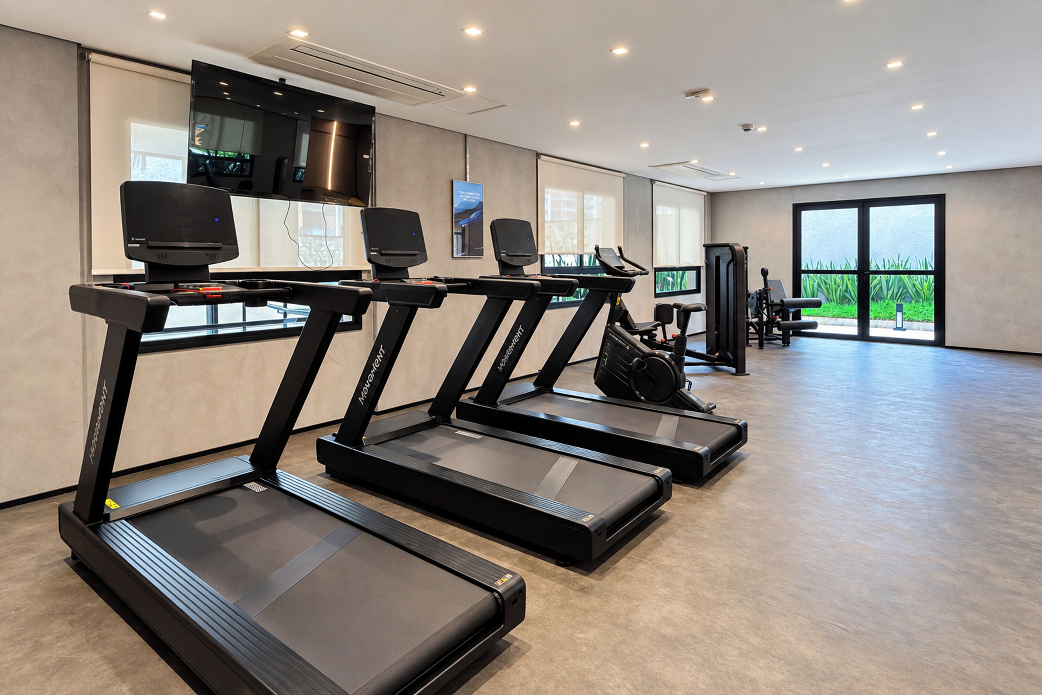 A gym with treadmills, exercise equipment, and large windows.