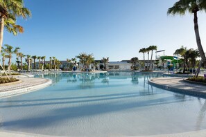 A large, clear swimming pool with palm trees and lounge chairs around it. - 6BR Windsor Cay Home w/ Private Pool (Clermont)