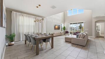 Un amplio espacio habitable con mesa de comedor, sofá y ventanas grandes.