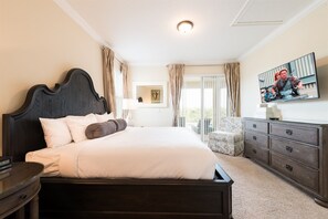 A bedroom with a large bed, a dresser, a chair, and a TV on the wall. - 6BR Home w/ Pool, Theater & Game Room (Kissimmee)