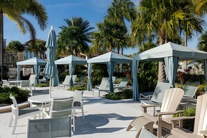 Outdoor seating areas with umbrellas, lounge chairs, and a poolside setting. - Solara Resort 6BR Home w/ Pool, Spa & Game Loft (Kissimmee)
