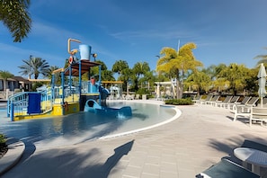 A water park with a wave machine, lounge chairs, and a pool area. - Solara Resort 6BR Home w/ Pool, Spa & Game Loft (Kissimmee)