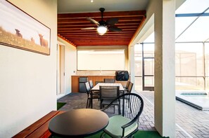 A patio area with a table and chairs, a ceiling fan, and a view of a swimming pool. - 7BR Windsor Cay Home w/ Pool & Game Room (Clermont)
