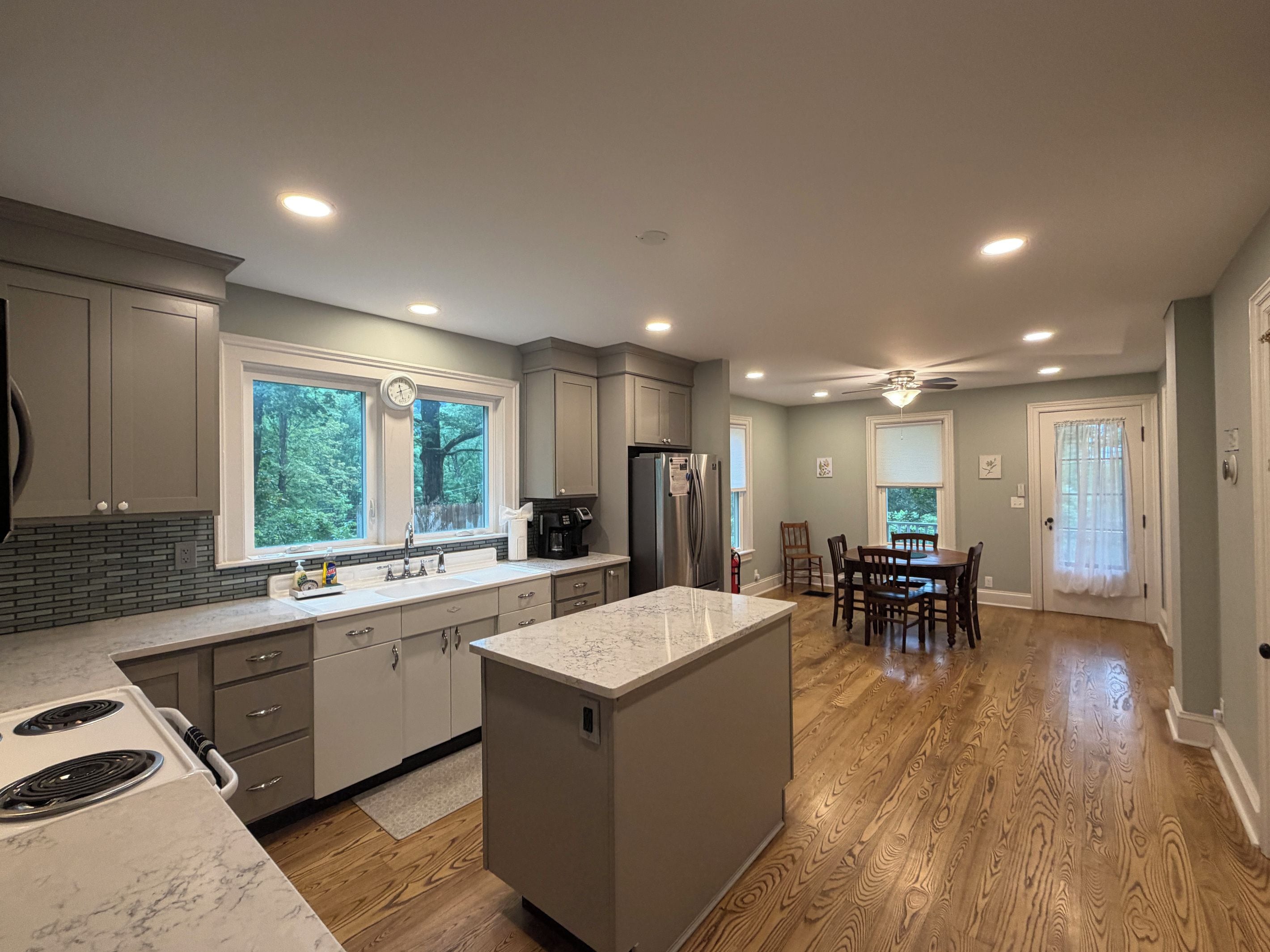 A modern kitchen with a central island, built-in appliances, and a dining area with a wooden floor.
