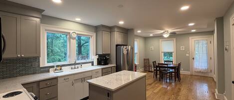 A modern kitchen with a central island, built-in appliances, and a dining area with a wooden floor.