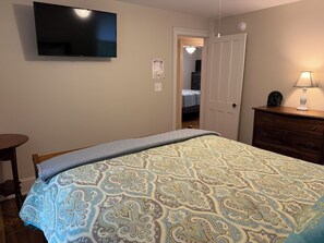 A bedroom with a bed, a dresser, a lamp, and a television on the wall. - Phoenix All Star - Charming 3-bdrm home on quiet country road (Cooperstown)
