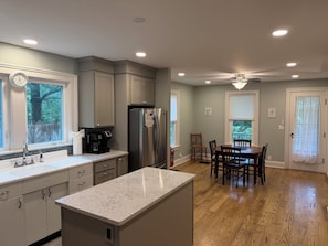 A kitchen with a marble countertop, stainless steel appliances, and a dining area with wooden chairs. - Phoenix All Star - Charming 3-bdrm home on quiet country road (Cooperstown)