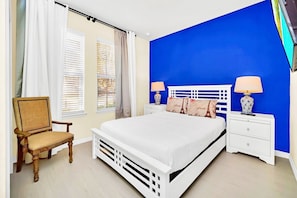 A bedroom with a white bed, two nightstands, a chair, and a blue accent wall. - 8br/6ba Luxury Villa, Private Pool, Disney (Kissimmee)