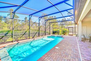 A covered outdoor swimming pool with a brick patio and a view of trees. - 8br/6ba Luxury Villa, Private Pool, Disney (Kissimmee)