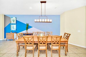 A dining area with a large wooden table and chairs, a hanging light fixture, and a blue accent wall. - 8br/6ba Luxury Villa, Private Pool, Disney (Kissimmee)