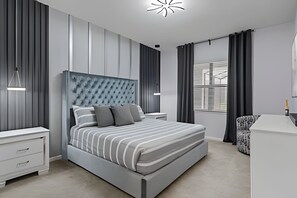 Ein modernes Schlafzimmer mit einem großen Bett, Nachttischen, einer Kommode und einem Fenster mit Vorhängen.