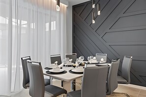 A modern dining area with a geometric wall design, a long table set for six, and contemporary chairs. - Paradiso Grande Luxury w/ Cinema, Games & Pool (Orlando)