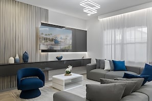 A modern living room with a sofa, coffee table, and a TV mounted on the wall. - Paradiso Grande Luxury w/ Cinema, Games & Pool (Orlando)