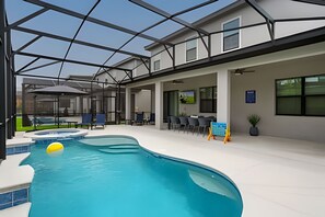 Ein Hallenbad mit Glasdach, Liegestühlen und einem Essbereich mit Tischen und Stühlen.