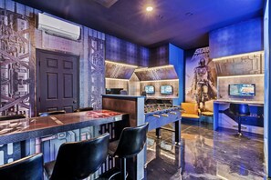 A room with a foosball table, a Star Wars-themed mural, and a Star Wars character poster. - Windsor Hills 6BR Home, Private Pool + Game Room (Kissimmee)