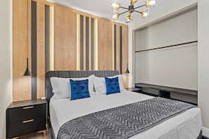 A modern bedroom with a bed, bedside tables, a wooden accent wall, and a ceiling light fixture. - Windsor Hills 6BR Home, Private Pool + Game Room (Kissimmee)