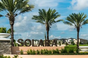 A sign with 'SOLARA' prominently displayed, surrounded by palm trees and modern buildings in the background. - Disney 6BR Villa w/ Pool & Themed Rooms (Kissimmee)