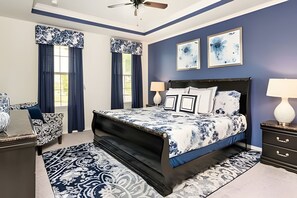 A bedroom with a large bed, two bedside tables, a nightstand, a ceiling fan, and artwork on the wall. - Disney 6BR Villa w/ Pool & Themed Rooms (Kissimmee)