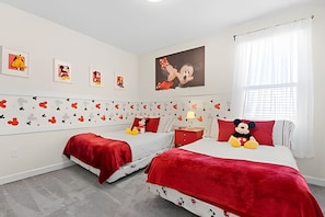 A bedroom with two beds, red bedding, Mickey Mouse plush toys, and wall art. - 6BR Villa w/ Pool & Themed Rooms (Kissimmee)