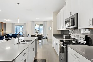 Een moderne keuken met witte kasten, roestvrijstalen apparatuur en een centraal eiland.