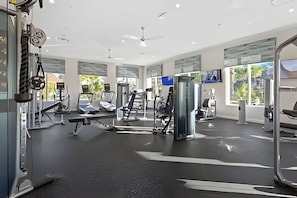 A modern gym with various exercise equipment, large windows, and a ceiling fan. - 6BR Villa w/ Pool & Themed Rooms (Kissimmee)