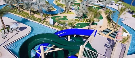 A water park with multiple slides and pools, surrounded by greenery and buildings.