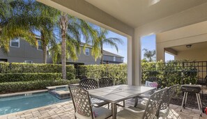 A covered patio with a pool, outdoor seating, and a view of a residential building. - Luxury 8BR Villa w/ Pool, Game & Theater Room (Kissimmee)