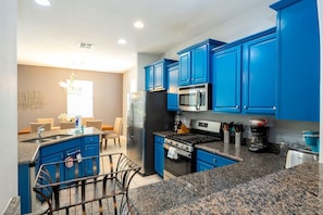 A modern kitchen with blue cabinets, stainless steel appliances, and granite countertops. - 6BR Solterra Home w/ Pool + Resort Access (Davenport)