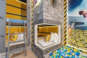 Ein Etagenbett mit Fenster, einer Leiter und einer Wand mit Minion-Motiv.