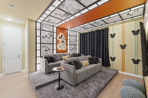 A living room with a grey sofa, a small round coffee table, and a large window with curtains. - Themed House With 7 Bedrooms Solara Resort (Kissimmee)