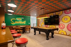 A pool table in a room with a neon sign reading 'The Simpsons' and a wall with a donut pattern. - 7bed Villa With Private Pool Solara Resort (Kissimmee)