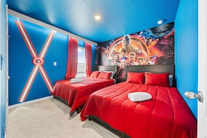 A hotel room with two beds, red bedding, a large Captain America shield mural, and a cosmic-themed wall art. - Solterra 6BR Lakeview + Pool & Game Room (Davenport)