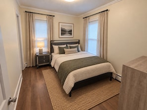 A bedroom with a bed, nightstand, lamp, and a framed picture on the wall. - Recent renovation, 2nd floor apt, near ASV (Oneonta)
