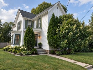 A two-story house with a front porch, a well-maintained lawn, and a variety of trees and shrubs. - Recent renovation, 2nd floor apt, near ASV (Oneonta)