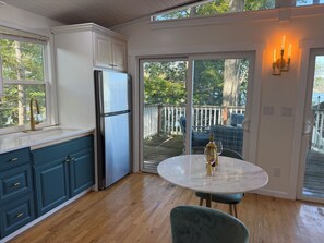 Une cuisine équipée d’un réfrigérateur, d’une table à manger avec des chaises et donnant sur la terrasse.