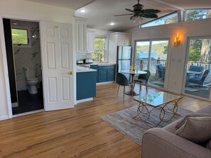 A modern kitchen with white cabinets, a dining area with a glass table, and a view of the outdoors. - 2 Bdrm, Total renovation, overlooking Canadarago (Richfield Springs)
