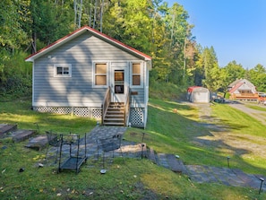 A small, single-story house with a porch, a garage, and a fenced yard. - Hatch's Coop - Awesome lake views, great studio cottage (Cooperstown)