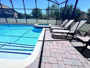 A swimming pool with a tiled edge, a small hot tub, and lounge chairs under a covered area. - 9BR Retreat for 20 w/ Game Room Champions Gate (Davenport)