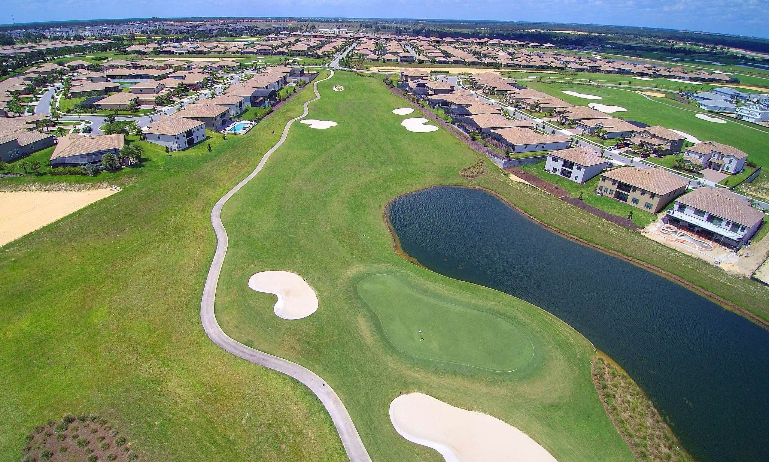 A golf course with a water hazard, sand bunkers, and a clubhouse.