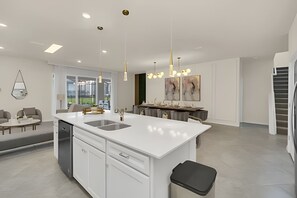 A modern kitchen with a central island, white cabinetry, and pendant lighting. - Luxury 10br Resort Home w/ Pool & Movie Theater (Clermont)